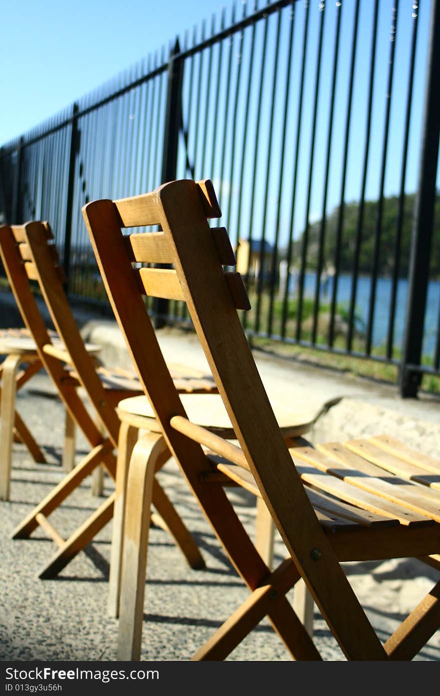 Chairs lined up along a fence near the coast. Chairs lined up along a fence near the coast.