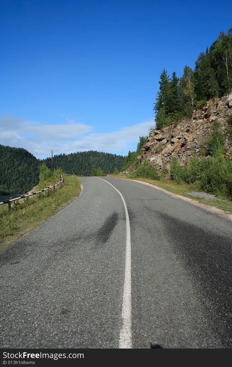 Road going near a rock under the blue sky. Road going near a rock under the blue sky