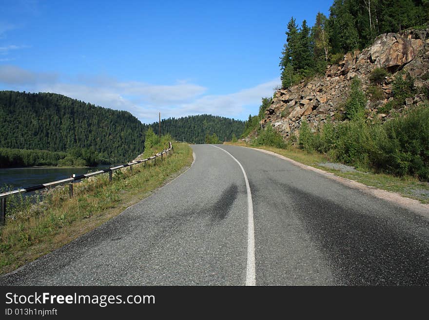 Road going near a rock under the blue sky. Road going near a rock under the blue sky