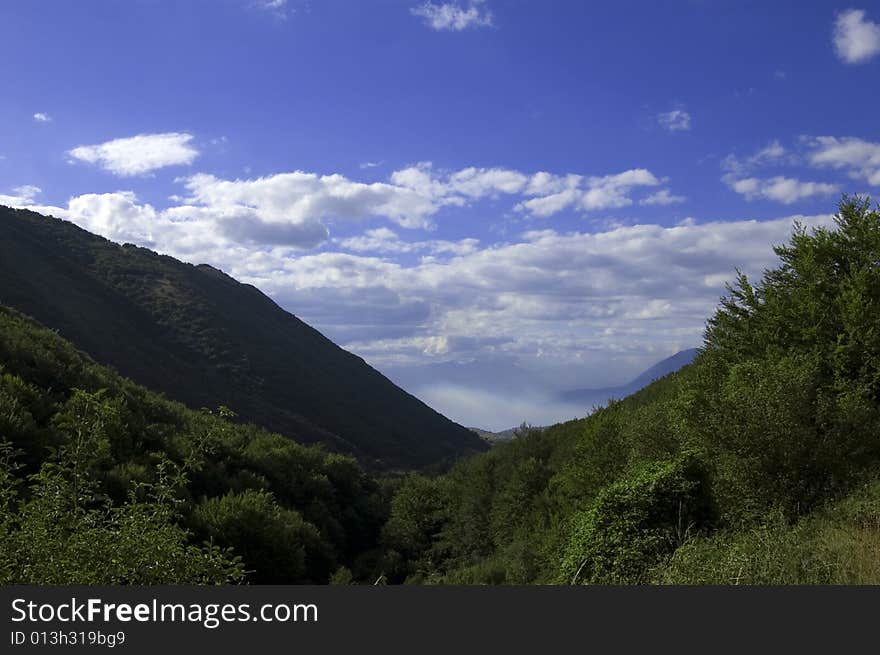 Mountain view in springtime with blue sky and fluffy clouds. Mountain view in springtime with blue sky and fluffy clouds.