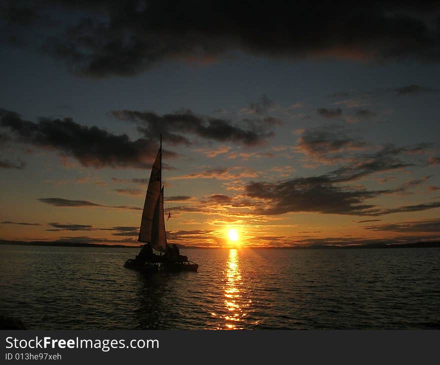 Sailboat at sunset with cloudy sky