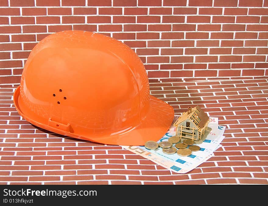 Hardhat with euro banknotes and model house on brick background. Hardhat with euro banknotes and model house on brick background