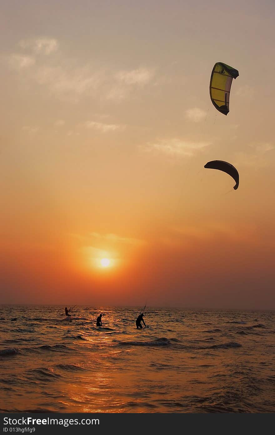 Silhouettes of kite surfers at sunset