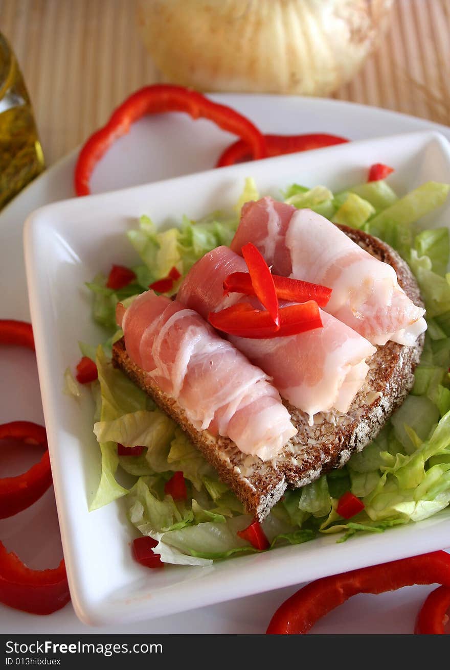 A piece of bread with bacconrolls on salad. A piece of bread with bacconrolls on salad