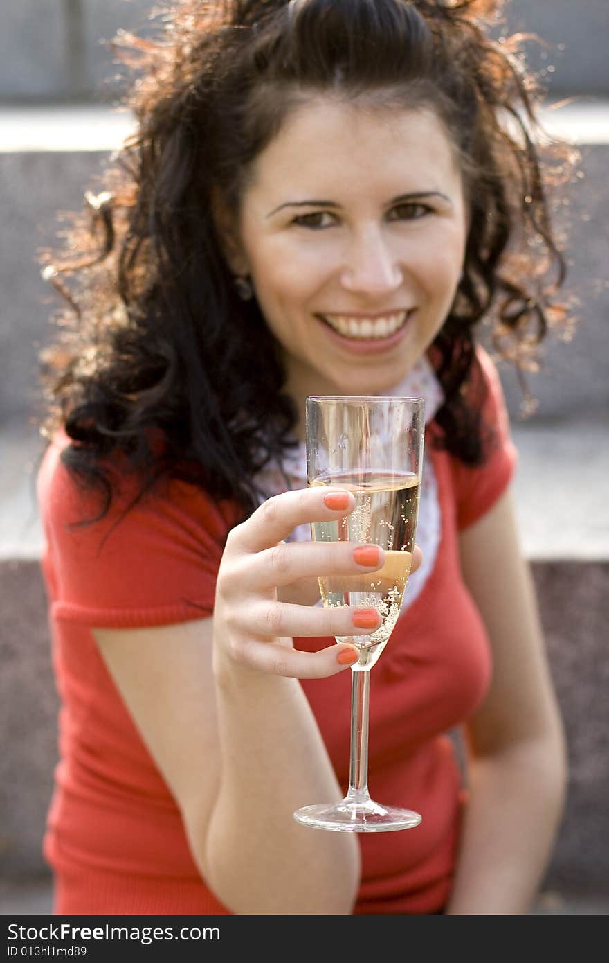 Outdoor portrait of smiling girl with champagne glass, focus on glass