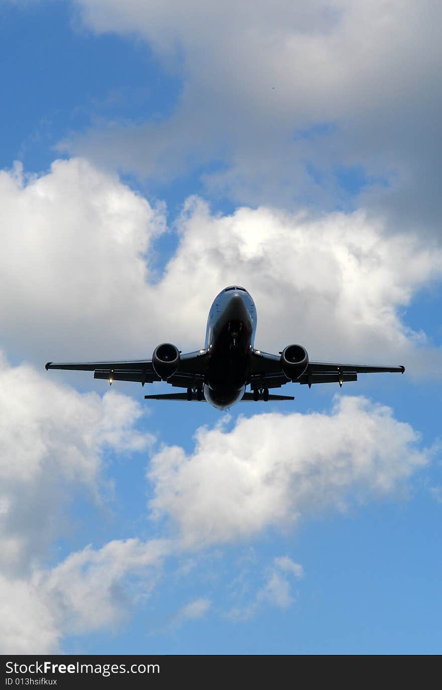 Jet airplane descending for landing. Clear blue sky on the background.