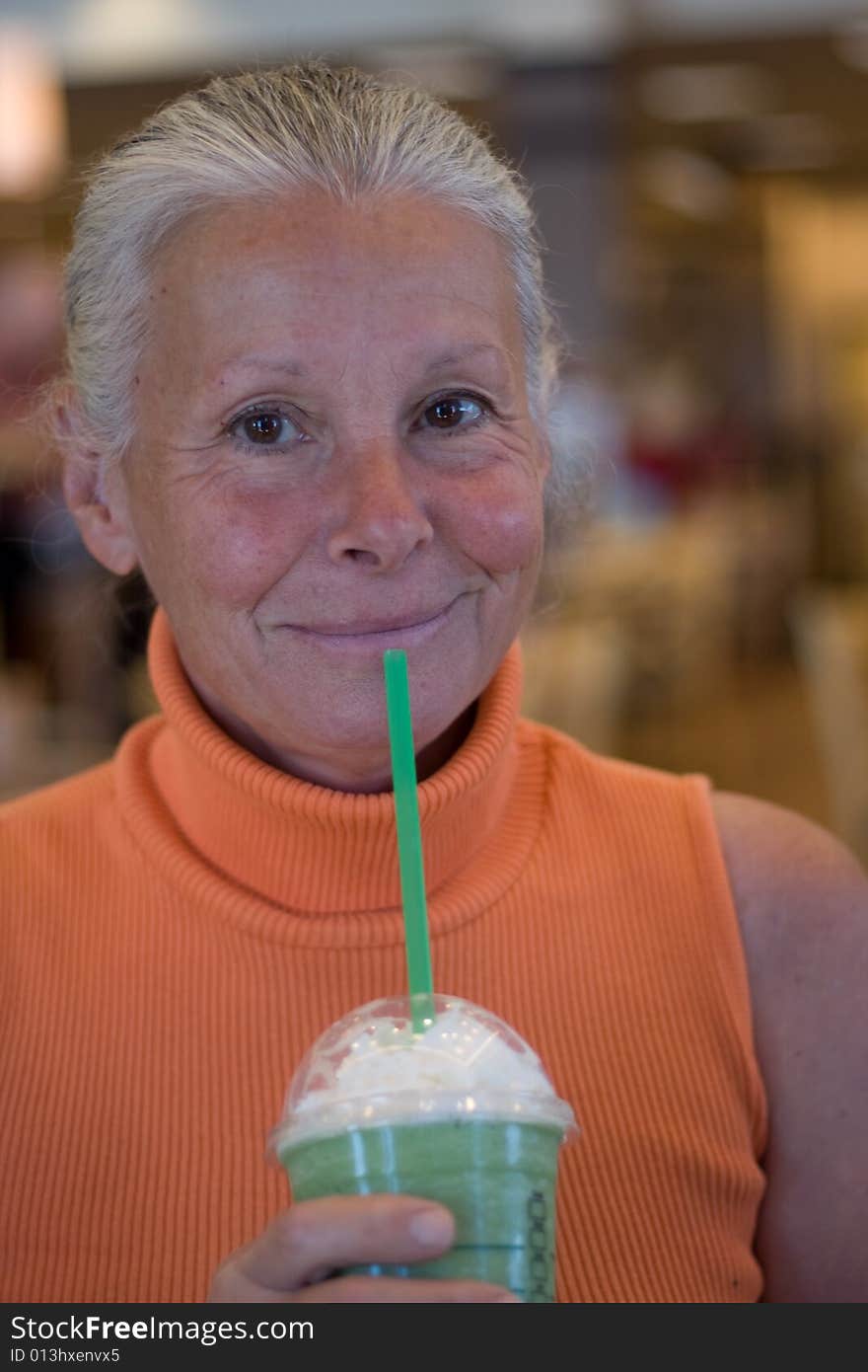 Senior woman drinking cold beverage in bookstore. Senior woman drinking cold beverage in bookstore