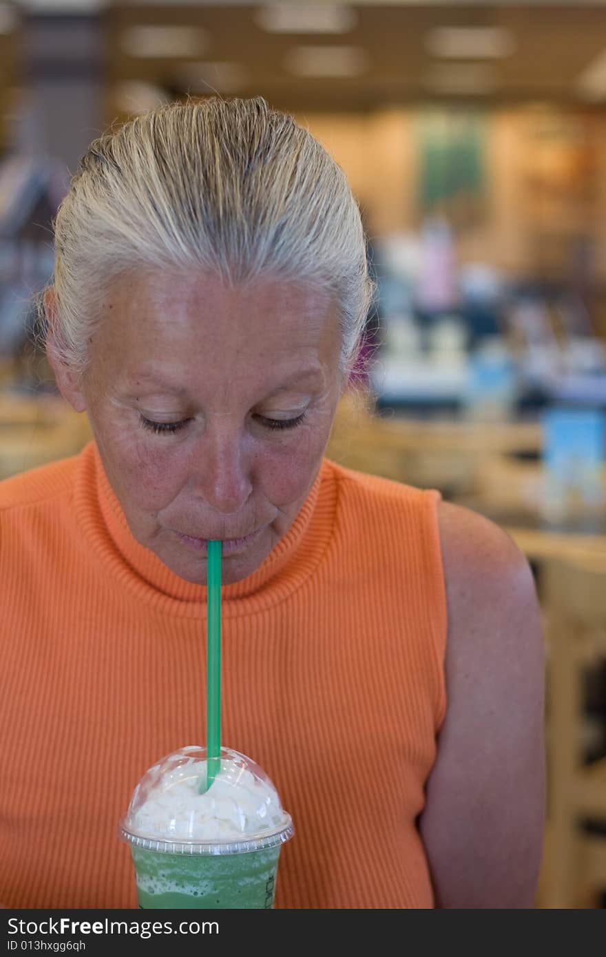 Senior woman drinking cold beverage in bookstore. Senior woman drinking cold beverage in bookstore