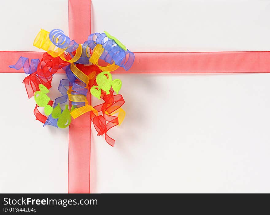 White gift box with red ribbon and yellow, blue, red bow