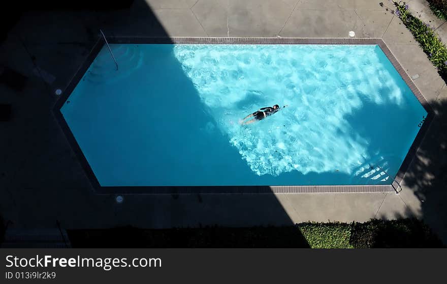 Aerial View of Male Swimmer in Shadowed Swimming Pool. Aerial View of Male Swimmer in Shadowed Swimming Pool