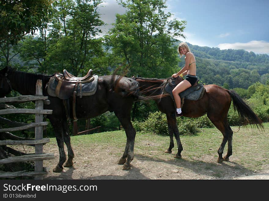 Beautiful making look younger girl sits in saddle on on walk in mountain. Beautiful making look younger girl sits in saddle on on walk in mountain