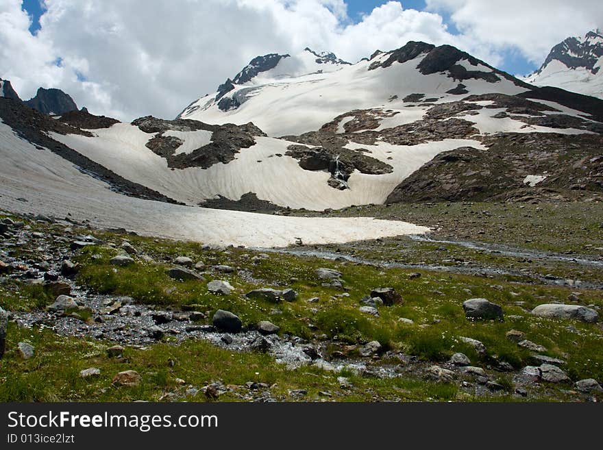 Flowering meadow with spring in mountains with glacier on background. Flowering meadow with spring in mountains with glacier on background