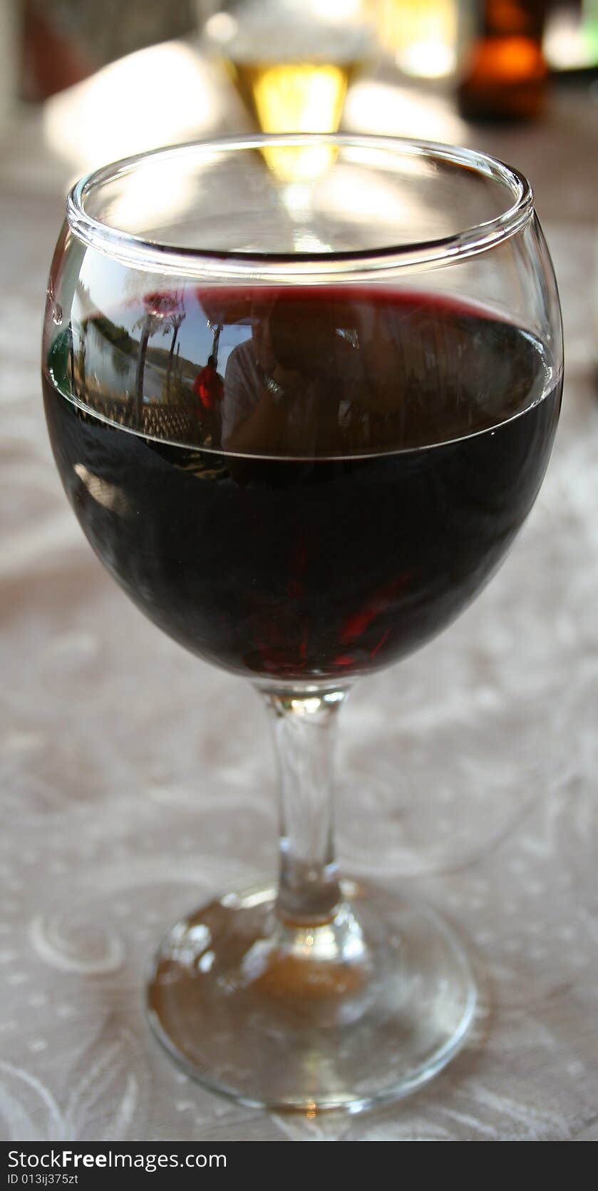 Glass with red vine on the table.