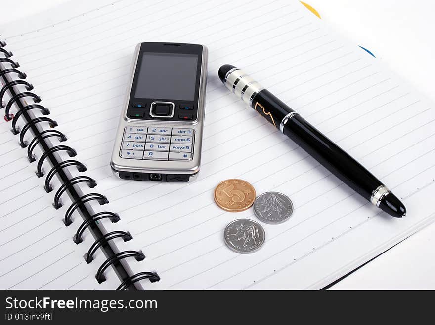 Pen,cellphone,coins and notebook