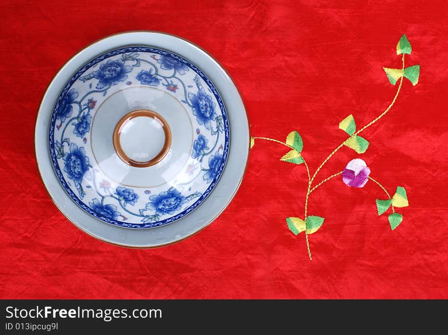 A tea cup on a Chinese style table cloth. A tea cup on a Chinese style table cloth