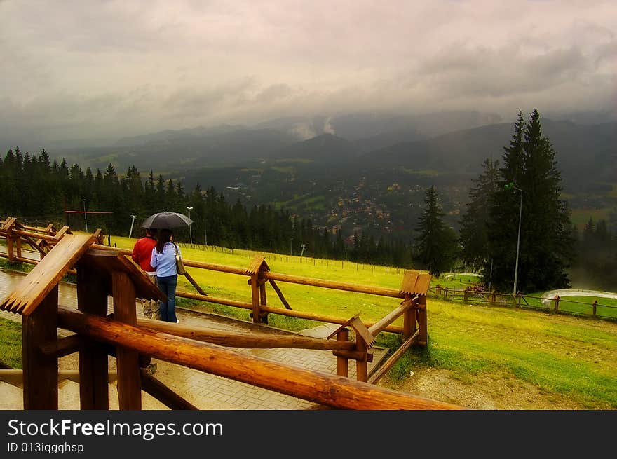 Young couple is looking on Zakopane from mountain in the rain. Young couple is looking on Zakopane from mountain in the rain