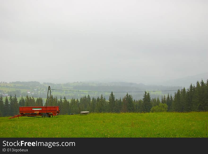 Red trailer on the foggy green hill. Red trailer on the foggy green hill