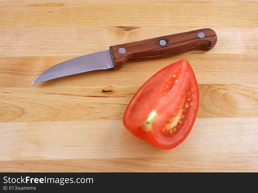 Fresh tomato with knife on kitchen board