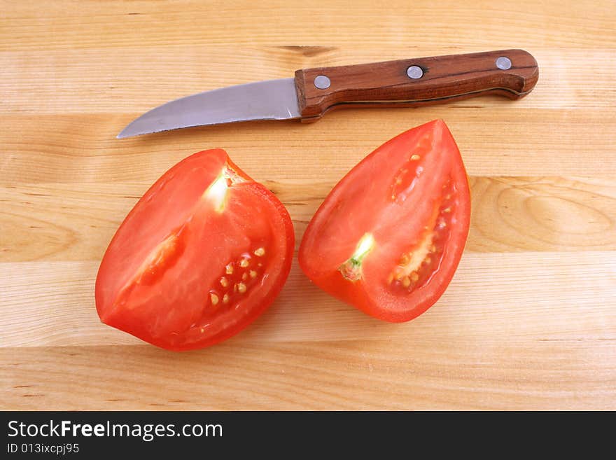 Fresh tomato with knife on kitchen board