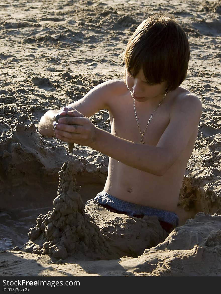 Young boy building sand scultures while sitting in mud hole. Young boy building sand scultures while sitting in mud hole