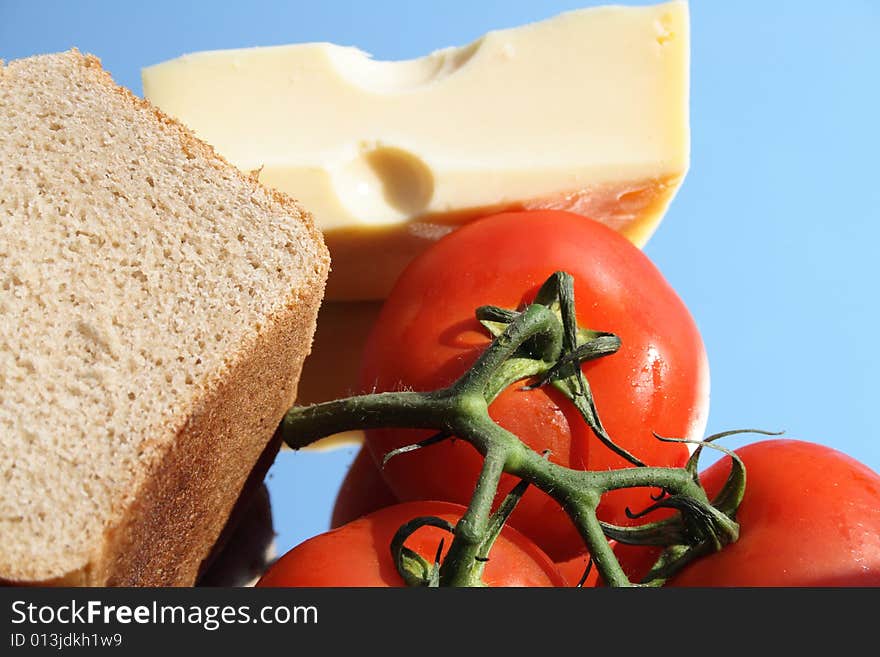 Rye-bread, tomatoes and cheese on blue background. Rye-bread, tomatoes and cheese on blue background