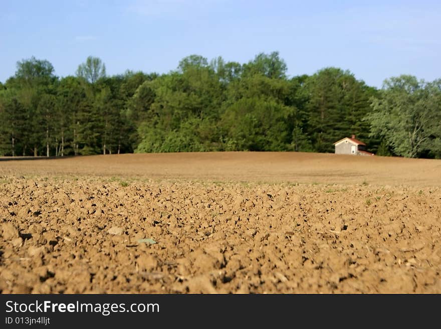 Focus on farmer's field with out of focus farmhouse in background. Focus on farmer's field with out of focus farmhouse in background.