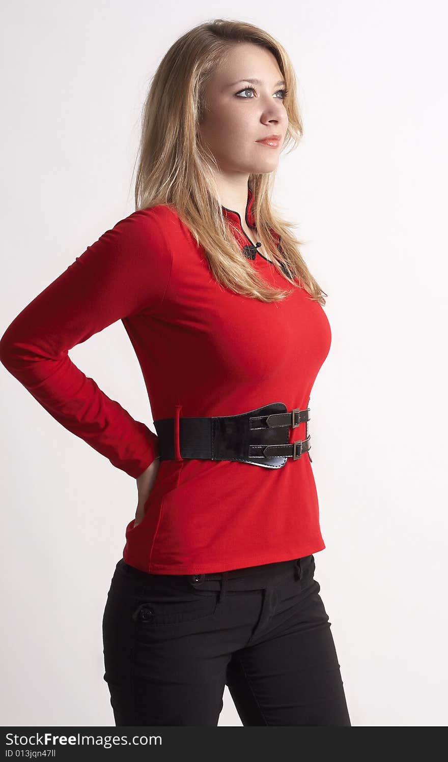 Portrait of beautiful blonde woman wearing a red top with a belt and stylish skinny pants . Not isolated