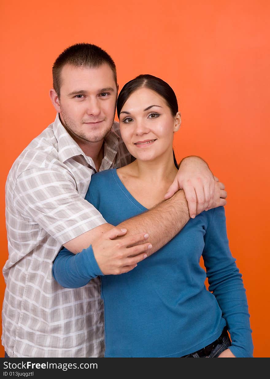 Casual couple together standing on orange background. Casual couple together standing on orange background