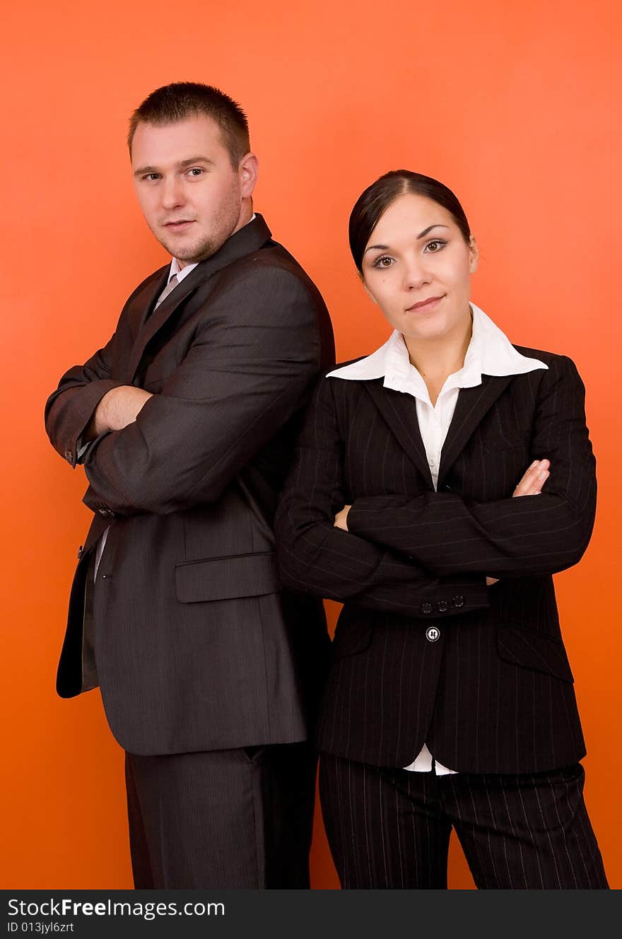 Businesswoman and businessman in team standing on orange background. Businesswoman and businessman in team standing on orange background