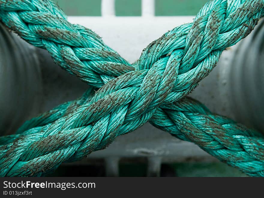 Green x-shaped rope over white mooring. Green x-shaped rope over white mooring