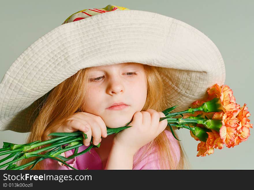 Small pensive girl in a big hat with pink flowers