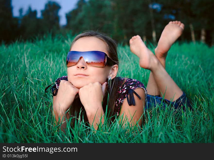 Young beautiful girl in sun glasses lying in green grass. Young beautiful girl in sun glasses lying in green grass