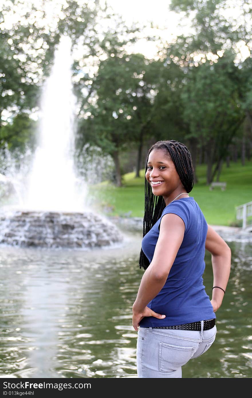 Pretty teen standing next to a fountain in the park. Pretty teen standing next to a fountain in the park