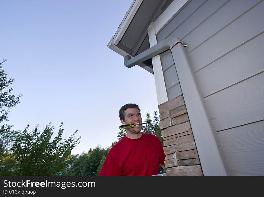 Man  with a screwdriver in his mouth and a smile on his face. Horizontally framed photo. Man  with a screwdriver in his mouth and a smile on his face. Horizontally framed photo