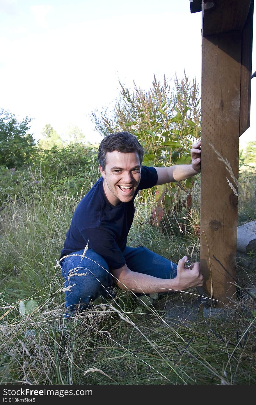 Man fixing a beam on a house with a wrench. Vertically framed photo. Man fixing a beam on a house with a wrench. Vertically framed photo.