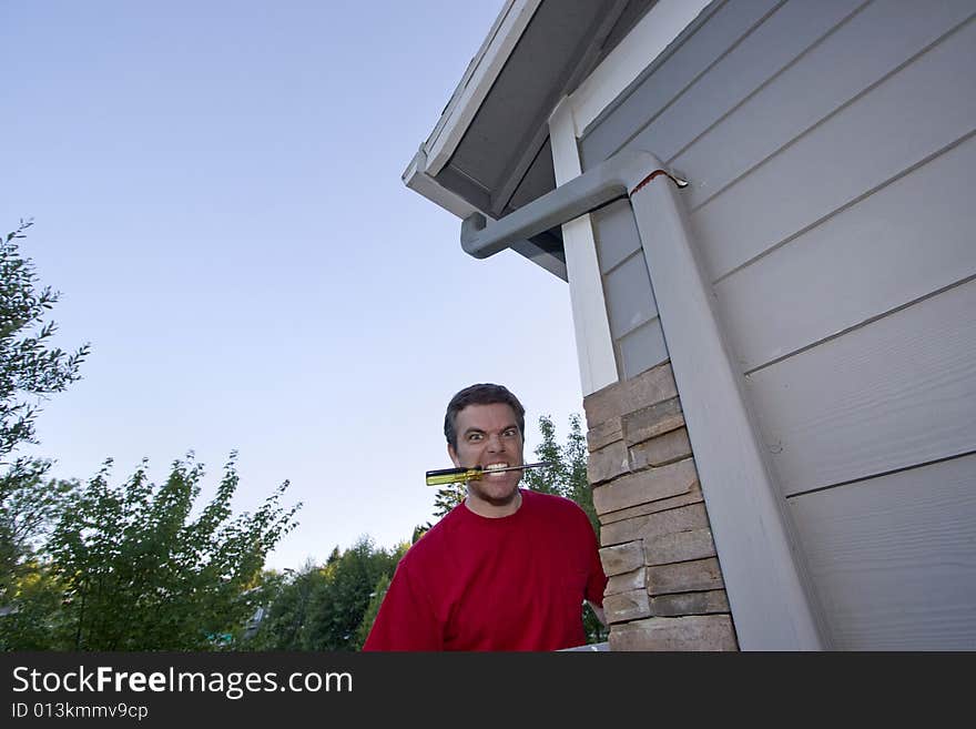 Man with a screwdriver in his mouth and a crazy look on his face. Horizontally framed photo. Man with a screwdriver in his mouth and a crazy look on his face. Horizontally framed photo