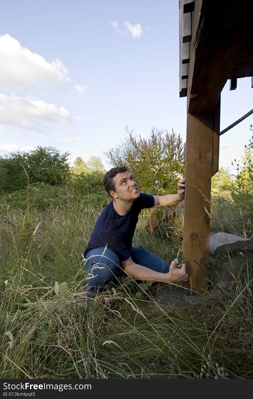 Man fixing a beam on a house with a wrench. Vertically framed photo. Man fixing a beam on a house with a wrench. Vertically framed photo.