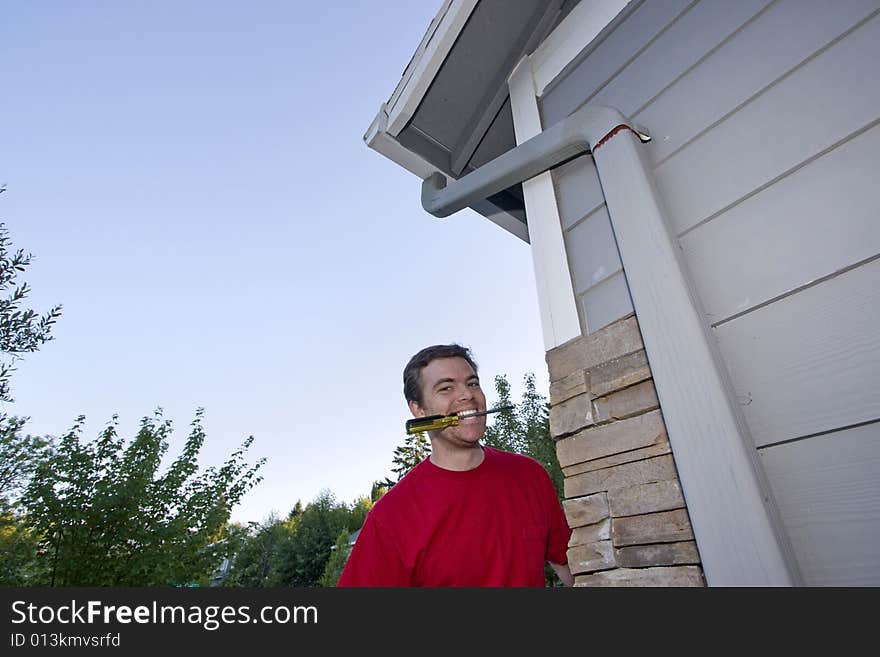 Man  with a screwdriver in his mouth and a smile on his face. Horizontally framed photo. Man  with a screwdriver in his mouth and a smile on his face. Horizontally framed photo