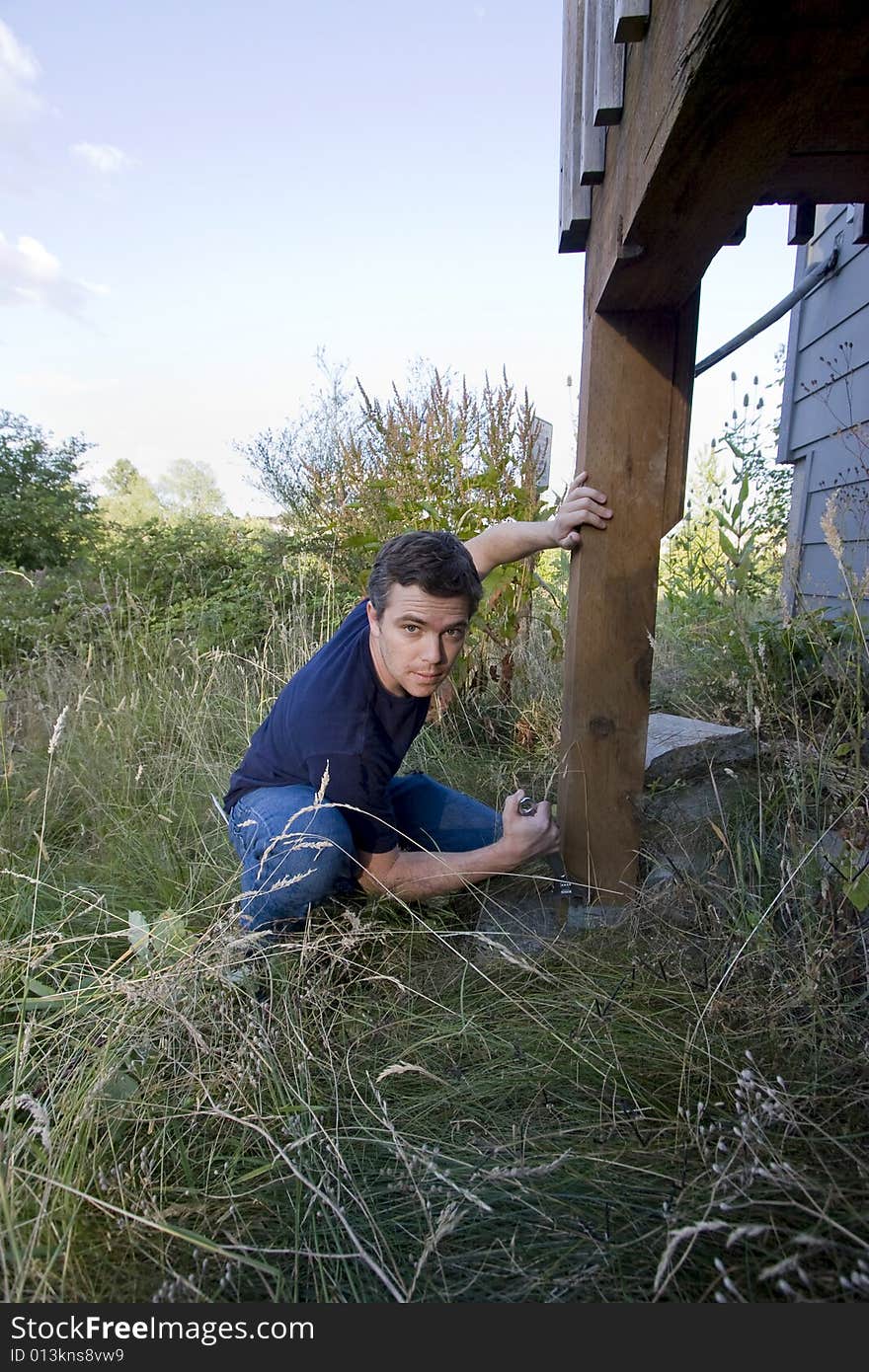 Man fixing a beam on a house with a wrench. Vertically framed photo. Man fixing a beam on a house with a wrench. Vertically framed photo.