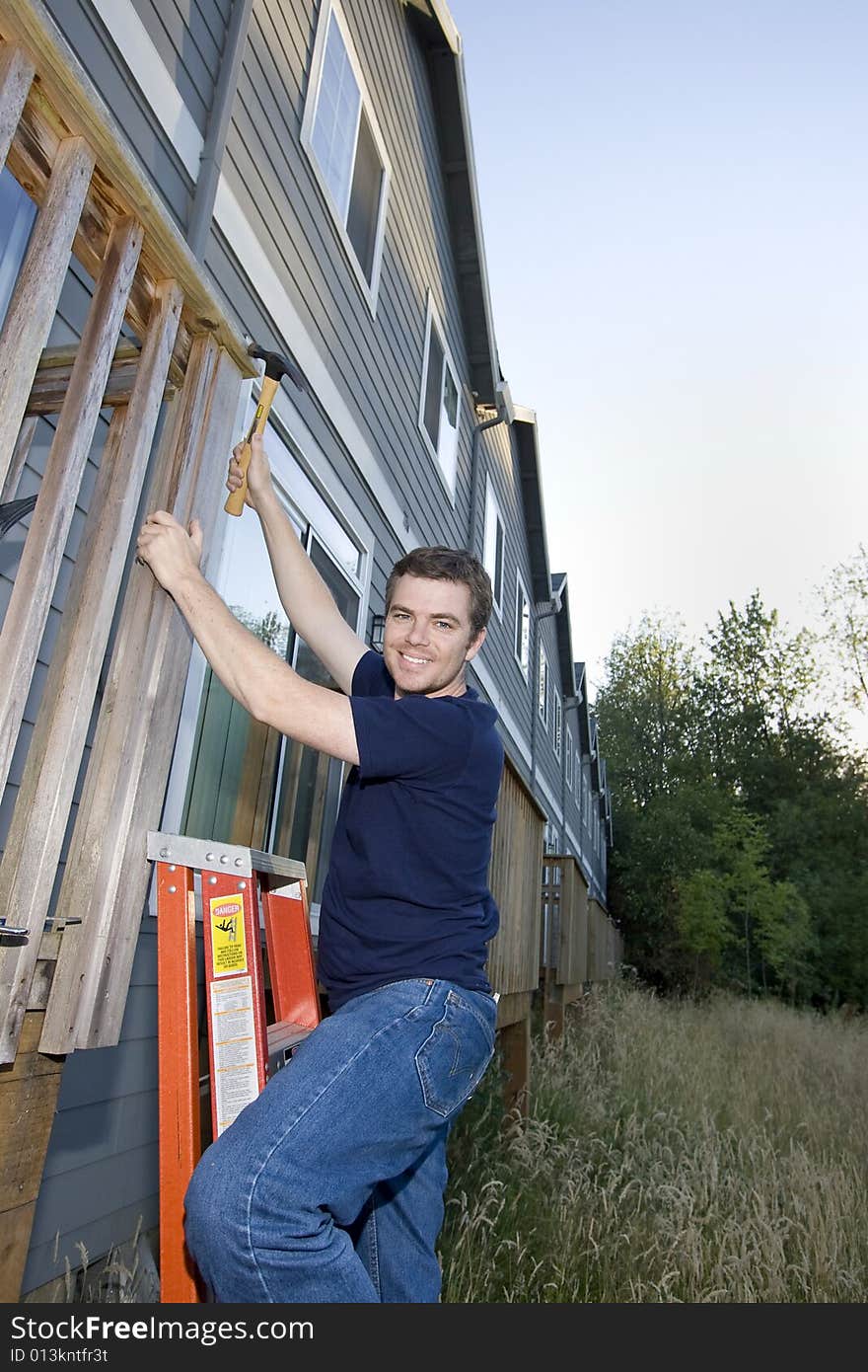 Smiling man using a hammer to fix a house. Vertically framed photo. Smiling man using a hammer to fix a house. Vertically framed photo.