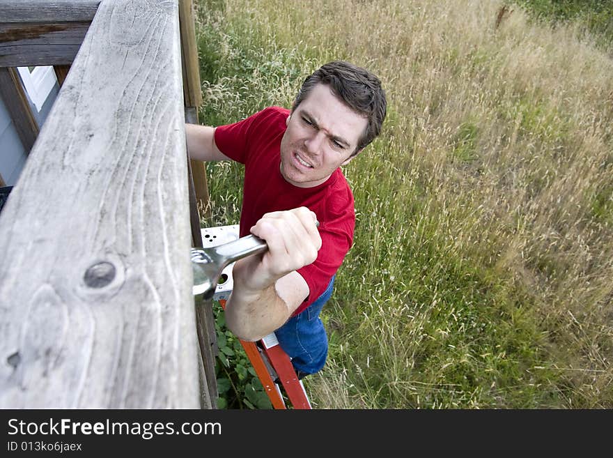 Frustrated man standing on a ladder fixing a porch with a wrench. Horizontally framed photo. Frustrated man standing on a ladder fixing a porch with a wrench. Horizontally framed photo.