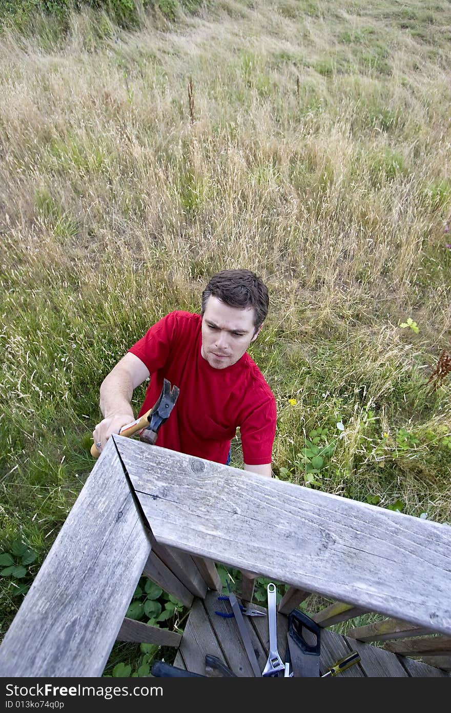 Aerial view of  man  on ladder hammering a porch. Vertically framed photo. Aerial view of  man  on ladder hammering a porch. Vertically framed photo.