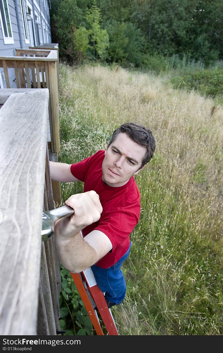 Frustrated man standing on a ladder fixing a porch with a wrench. Vertically framed photo. Frustrated man standing on a ladder fixing a porch with a wrench. Vertically framed photo.