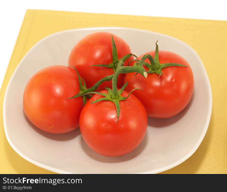 Bunch of tomato on white plate and place mat. Bunch of tomato on white plate and place mat