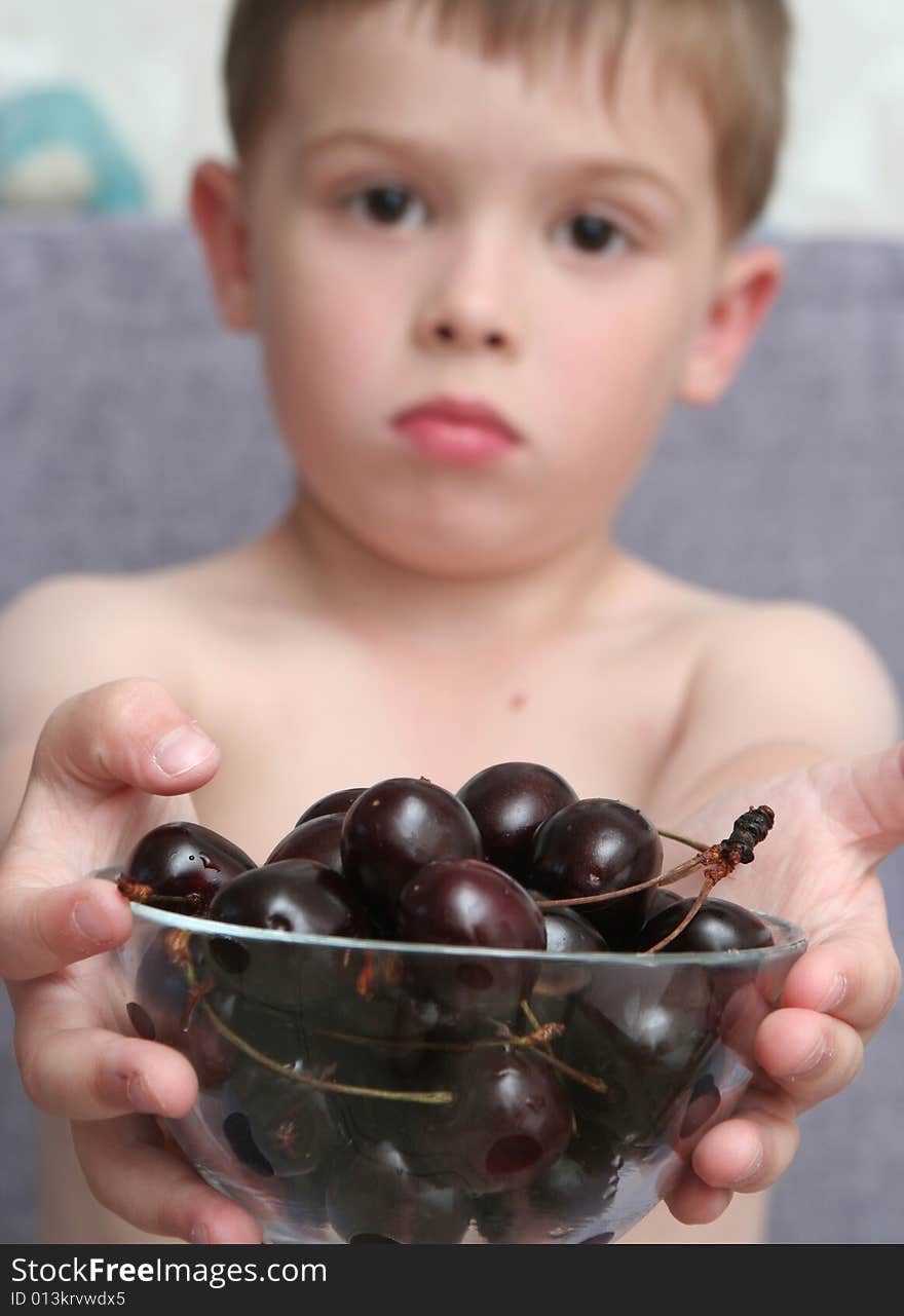 The boy holds a bowl with berries in hands