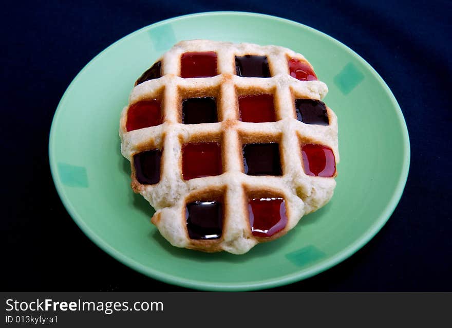 Waffles with jam on green plate  isolated on black background