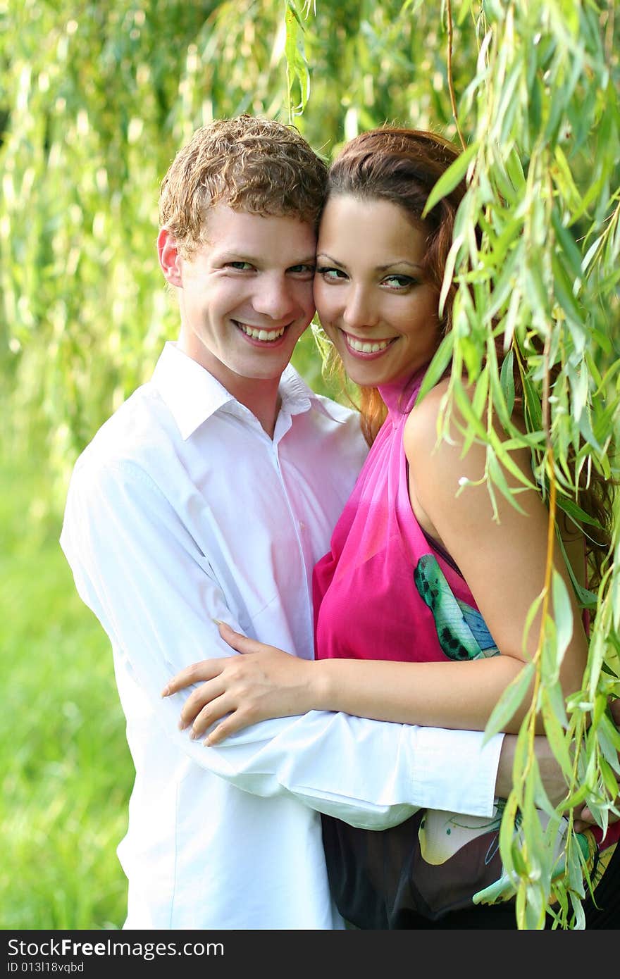 Cute young couple under green willow. Cute young couple under green willow