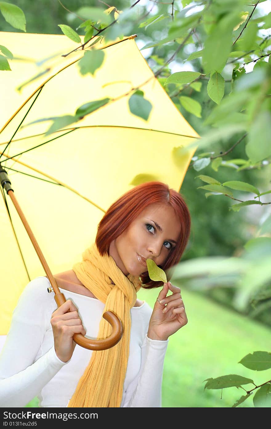 Beautiful young girl under yellow umbrella in the autumn park. Beautiful young girl under yellow umbrella in the autumn park