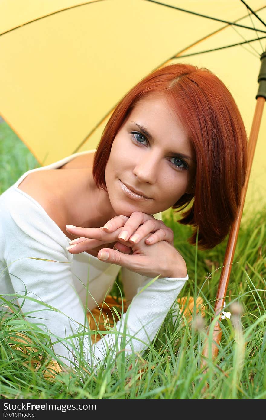 Beautiful girl relaxing on grass under yellow umbrella. Beautiful girl relaxing on grass under yellow umbrella