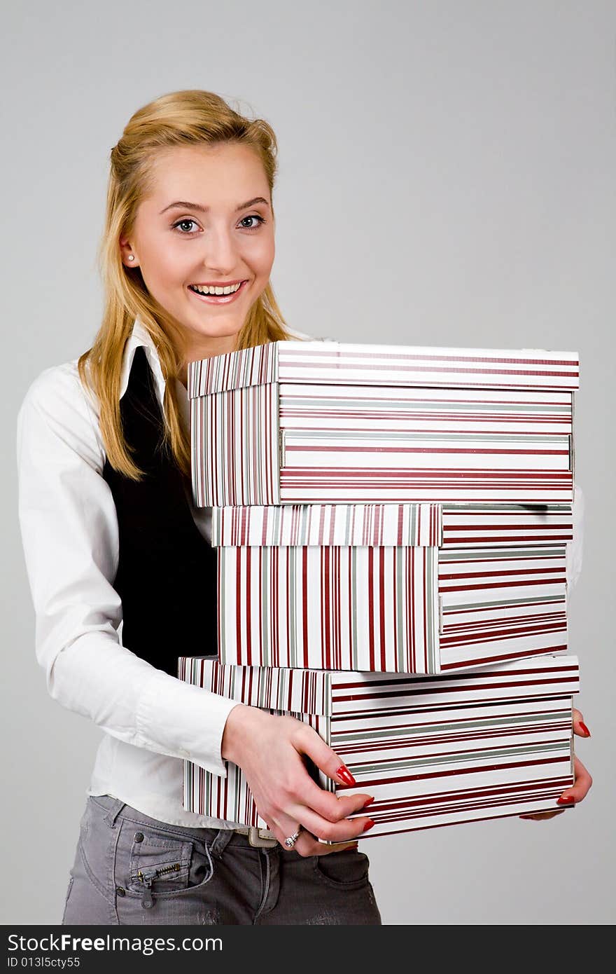 Smiling young woman holding a stack of boxes indoors. Smiling young woman holding a stack of boxes indoors
